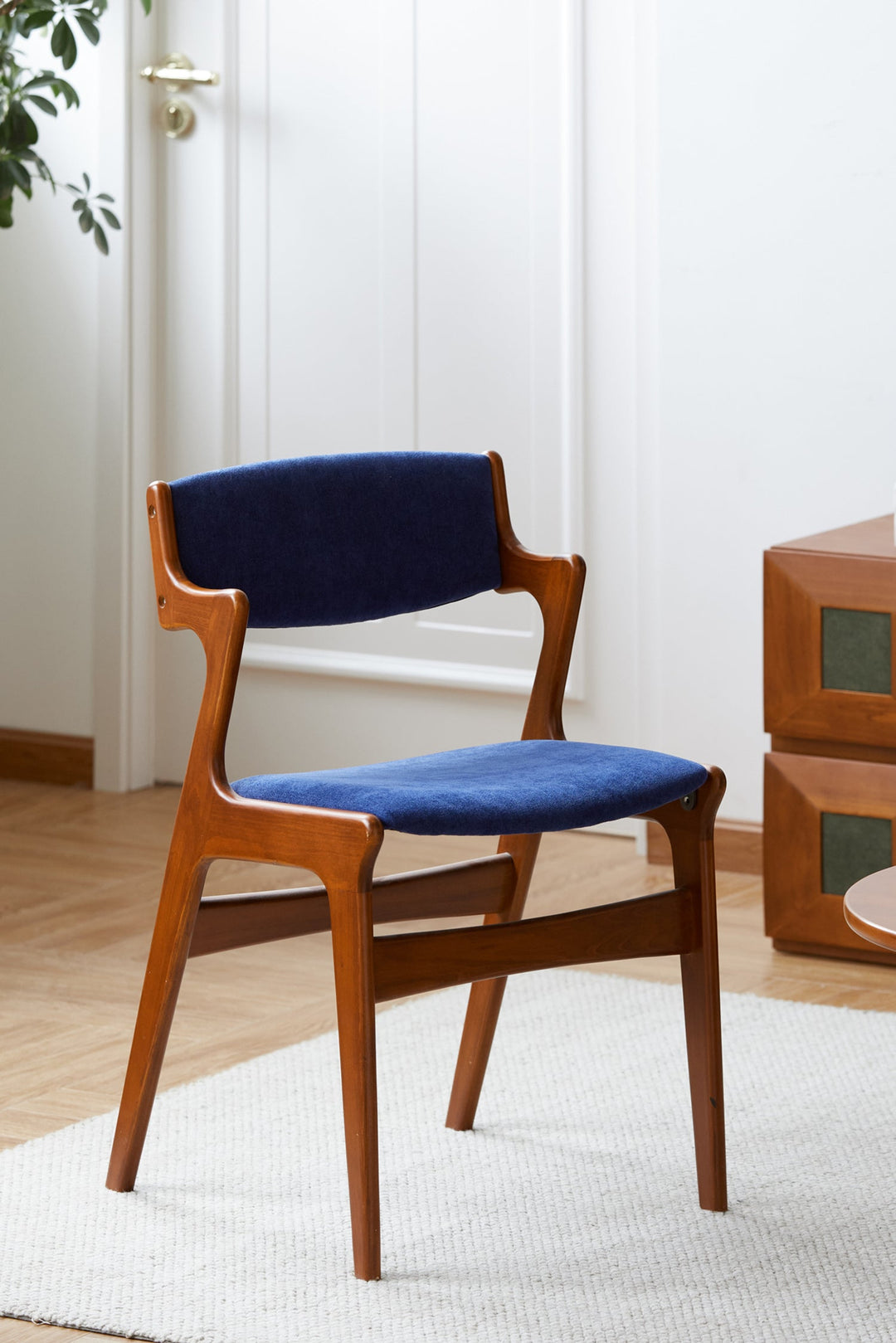 Blue fabric Scandinavian dining chair with curved wood frame, adding modern flair to dining interiors.
